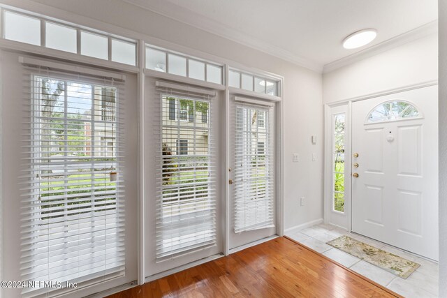 foyer entrance featuring light wood-type flooring, ornamental molding, and a healthy amount of sunlight