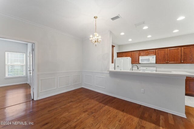 kitchen with white appliances, pendant lighting, crown molding, and wood-type flooring