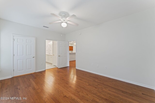 unfurnished bedroom featuring wood-type flooring, ensuite bathroom, and ceiling fan