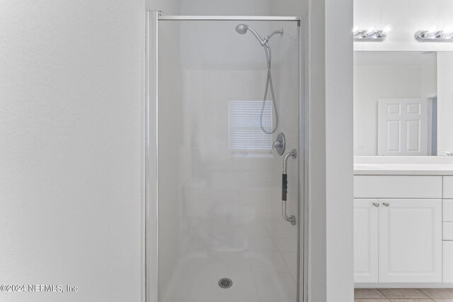 bathroom with tile patterned floors, an enclosed shower, and vanity