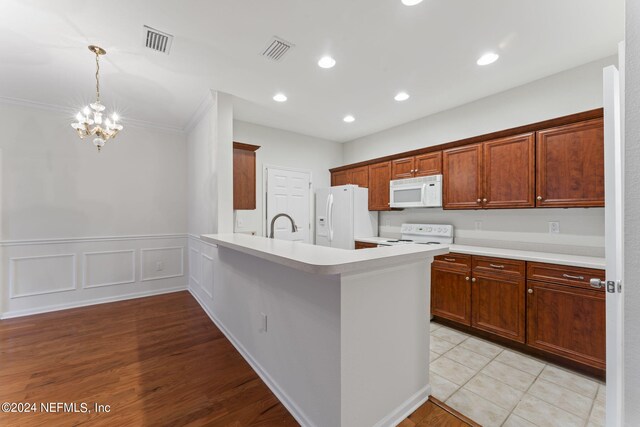 kitchen with ornamental molding, white appliances, a chandelier, kitchen peninsula, and light hardwood / wood-style floors