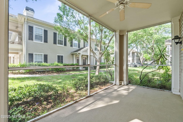 unfurnished sunroom featuring a ceiling fan and a wealth of natural light