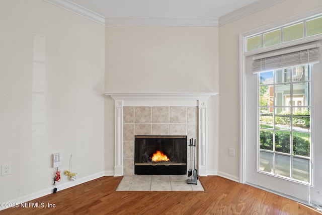 interior details with a tile fireplace, ornamental molding, and wood finished floors