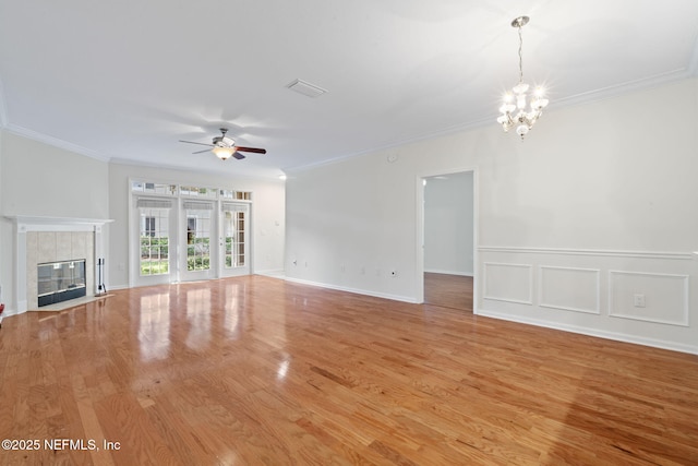 unfurnished living room featuring ornamental molding, a fireplace, light wood-style floors, visible vents, and ceiling fan with notable chandelier