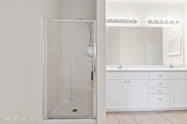 bathroom featuring a shower stall, tile patterned floors, double vanity, and a sink