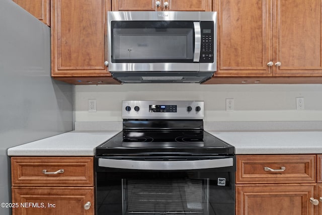 kitchen with brown cabinets, appliances with stainless steel finishes, light countertops, and tile patterned flooring