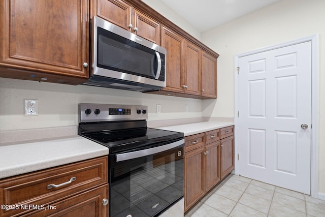 kitchen with brown cabinets, light countertops, appliances with stainless steel finishes, and light tile patterned flooring