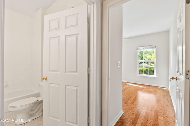hall featuring light wood-style flooring and baseboards
