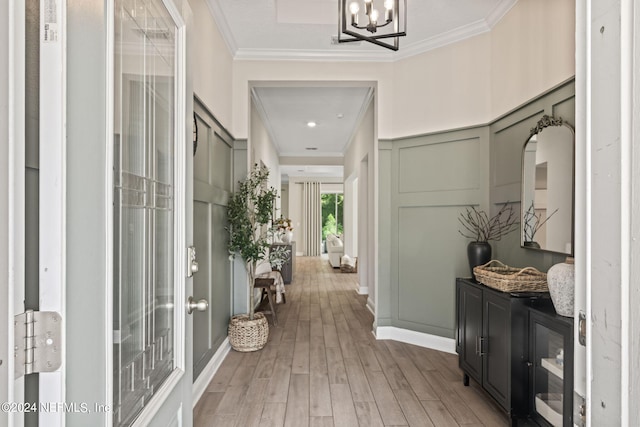 corridor featuring wood-type flooring, ornamental molding, and a chandelier