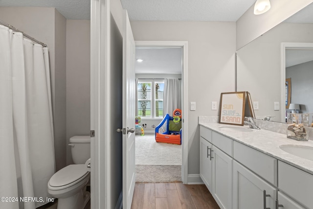 bathroom with hardwood / wood-style floors, vanity, a textured ceiling, and toilet