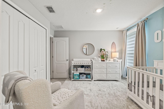 bedroom with a closet, wood-type flooring, a textured ceiling, and a nursery area