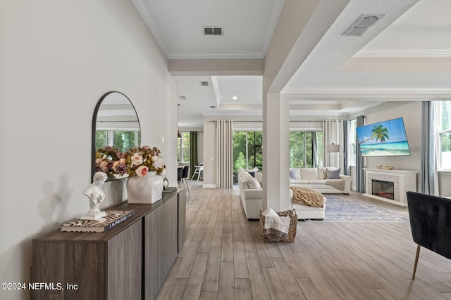 corridor featuring a wealth of natural light, crown molding, and light hardwood / wood-style floors