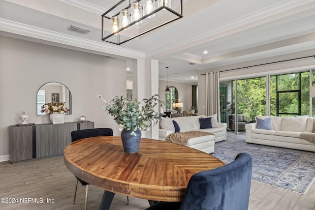 dining room with light wood-type flooring, a textured ceiling, a tray ceiling, crown molding, and a chandelier