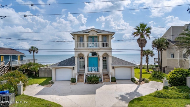 view of front of home featuring stucco siding, covered porch, concrete driveway, a balcony, and stairs