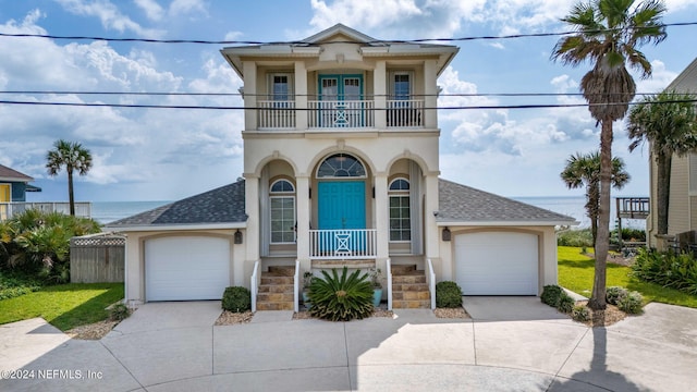 view of front facade featuring a water view, covered porch, a balcony, and a garage