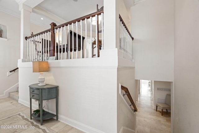 stairway featuring baseboards, crown molding, and a towering ceiling