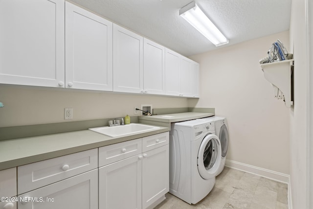 washroom featuring sink, washer and dryer, a textured ceiling, and cabinets