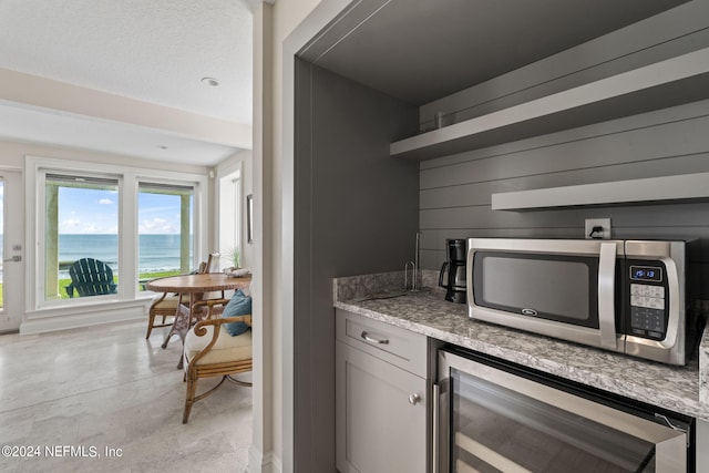 bar featuring stainless steel microwave and beverage cooler