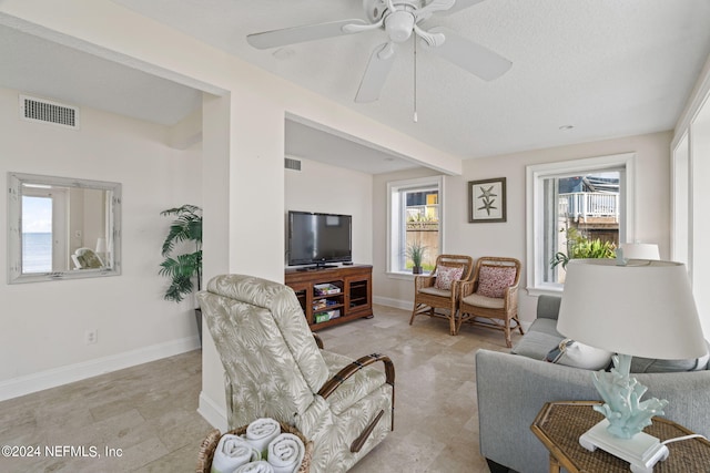 living room featuring ceiling fan, a textured ceiling, and plenty of natural light