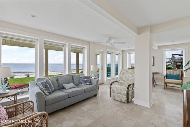 living room featuring a beach view, a healthy amount of sunlight, a water view, and ceiling fan