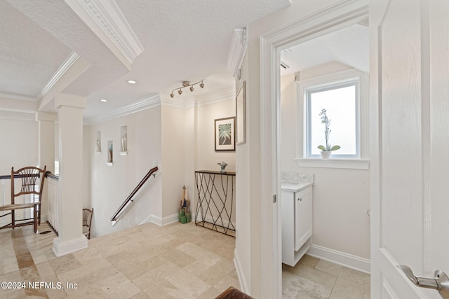 hall featuring crown molding, a textured ceiling, and decorative columns