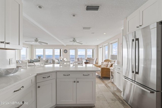 kitchen featuring visible vents, a peninsula, open floor plan, and freestanding refrigerator