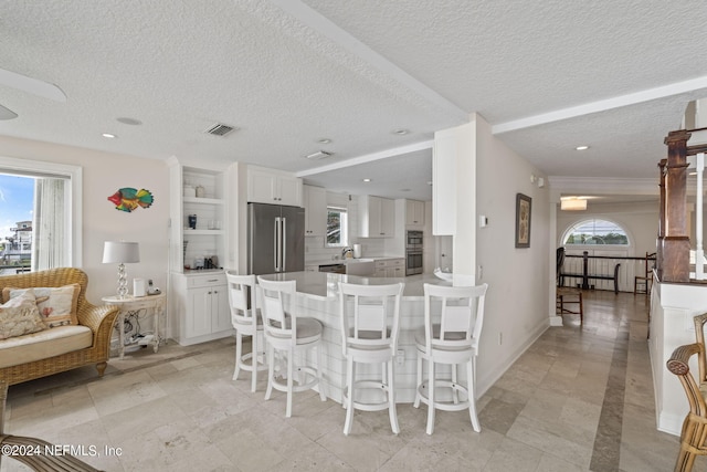 kitchen featuring a breakfast bar area, white cabinetry, kitchen peninsula, and stainless steel appliances