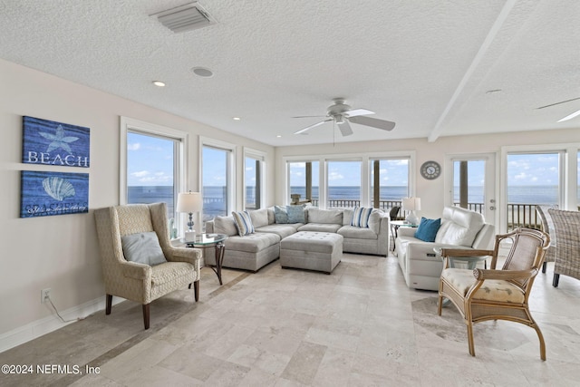 living room with plenty of natural light, a ceiling fan, visible vents, and baseboards