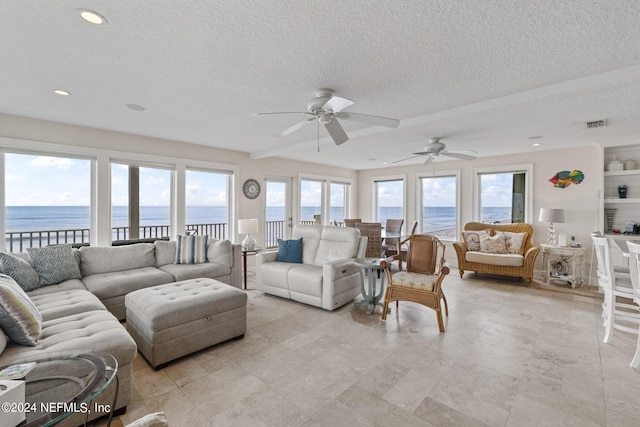 living room with a water view, a healthy amount of sunlight, and a textured ceiling