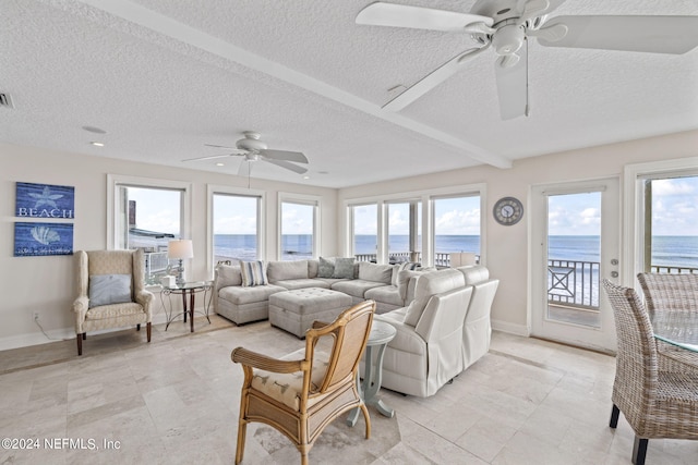 living room with a water view, ceiling fan, and plenty of natural light