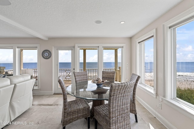 dining area featuring a water view, a textured ceiling, and plenty of natural light