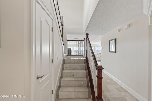 stairway with tile patterned floors and a textured ceiling