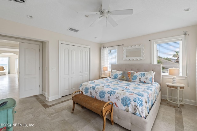 bedroom featuring baseboards, visible vents, arched walkways, and a closet