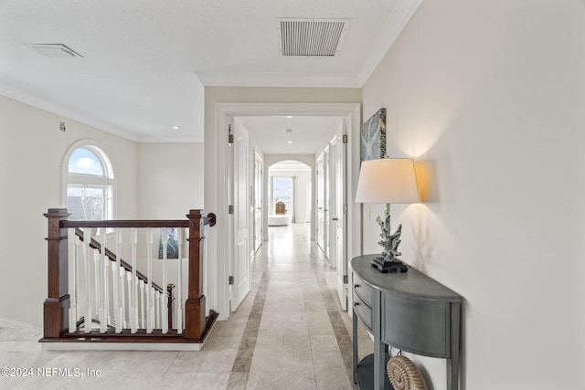 corridor with an upstairs landing, visible vents, arched walkways, and crown molding