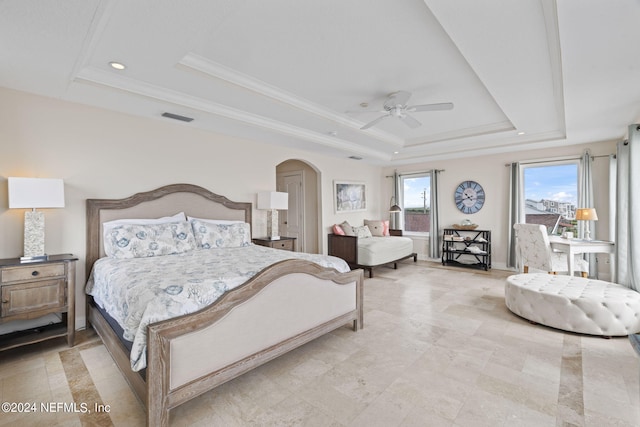 bedroom featuring a tray ceiling, arched walkways, visible vents, and crown molding