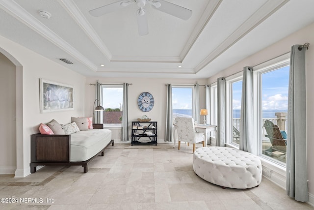 sitting room with a tray ceiling, arched walkways, plenty of natural light, and ornamental molding