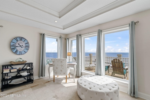 sitting room featuring baseboards, crown molding, a tray ceiling, and a water view