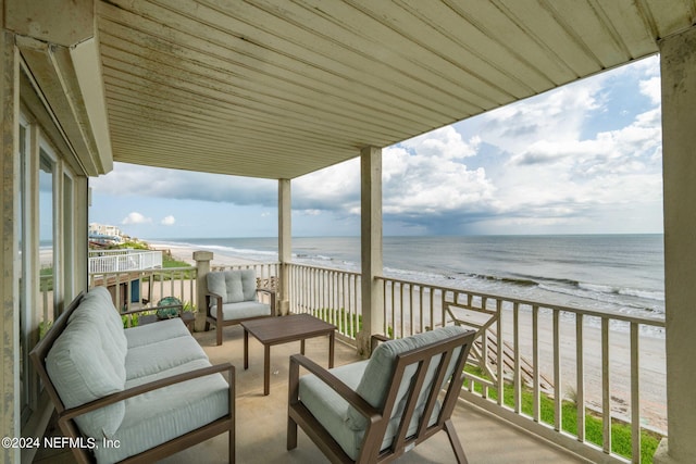 balcony with a view of the beach, a water view, and an outdoor hangout area