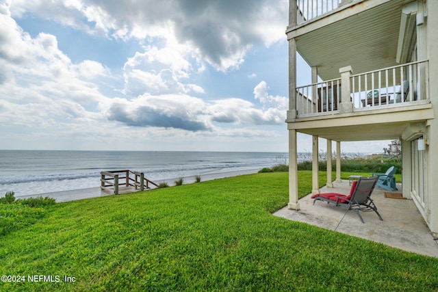 view of yard featuring a patio, a water view, and a beach view