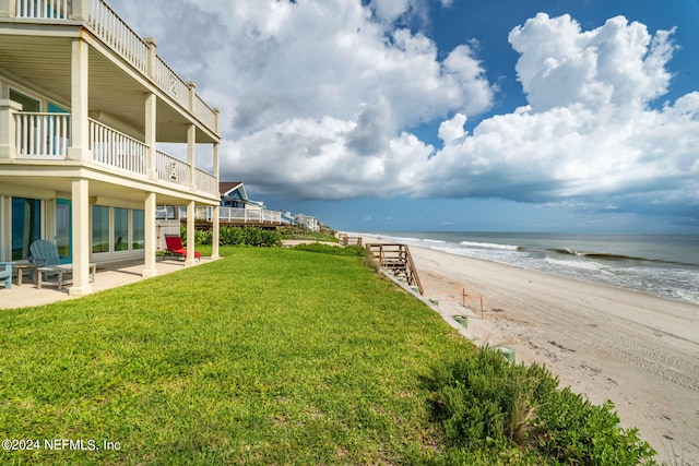 view of yard featuring a patio area, a water view, and a beach view