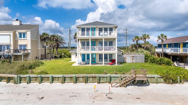 rear view of property with a patio area, a balcony, and a lawn