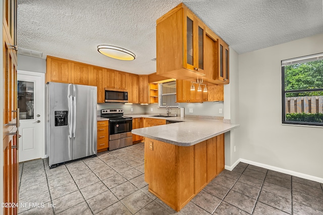 kitchen featuring a textured ceiling, kitchen peninsula, stainless steel appliances, and sink