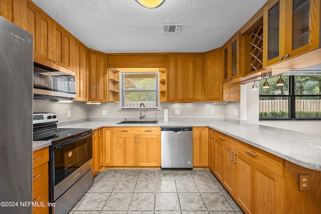 kitchen featuring appliances with stainless steel finishes, a textured ceiling, light tile patterned floors, and sink