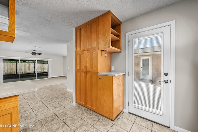 interior space with a textured ceiling, a healthy amount of sunlight, ceiling fan, and light tile patterned flooring