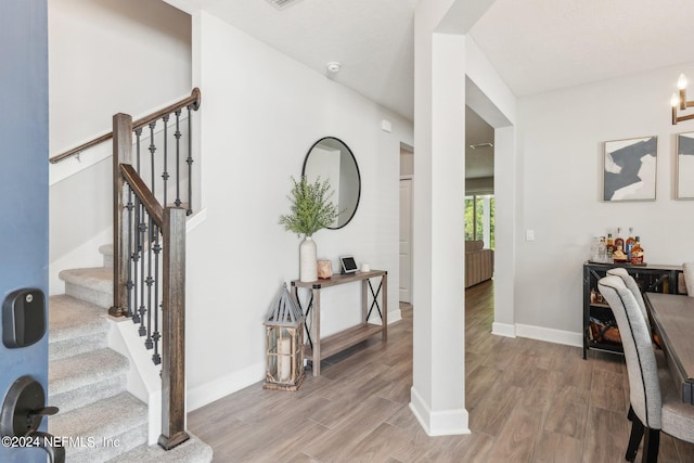 stairway with a textured ceiling, hardwood / wood-style flooring, and bar