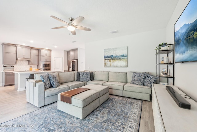 living room featuring light wood-type flooring and ceiling fan