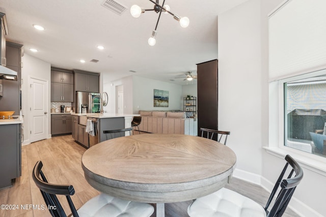 dining space featuring ceiling fan with notable chandelier and light hardwood / wood-style floors