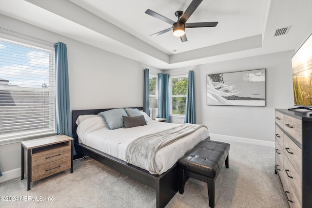 carpeted bedroom featuring a tray ceiling and ceiling fan