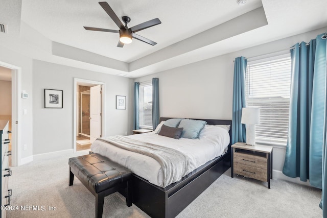 carpeted bedroom with a tray ceiling, ceiling fan, and connected bathroom