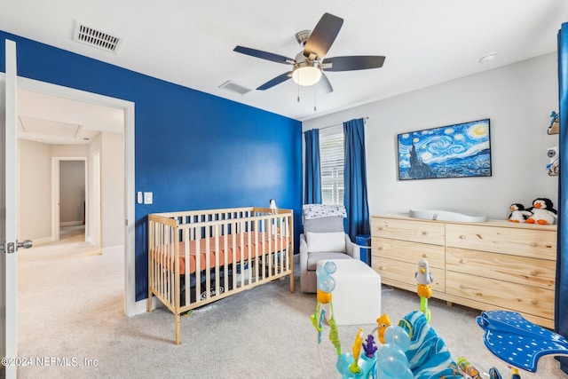 bedroom featuring ceiling fan, carpet, and a crib